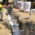 A trench with pipes partially covered by Gilsulate, a white powdery substance